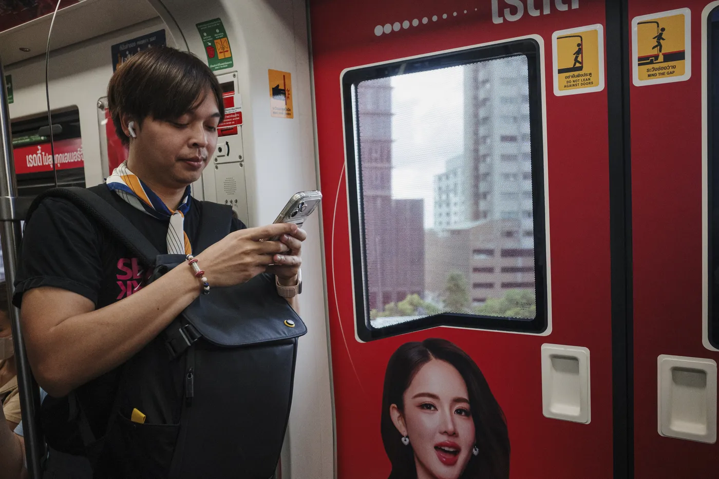 Arm on a Bangkok train answering outreach messages on a phone